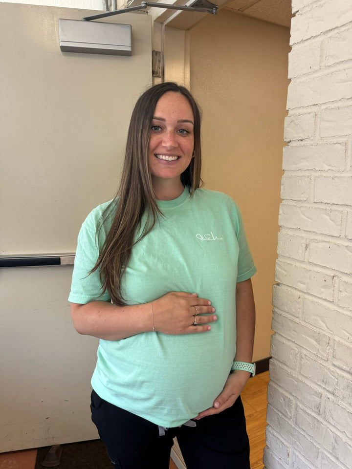 Pregnant woman wearing the Ladyspinedoc Heart of Medicine Tee Shirt in Island Reef Green 