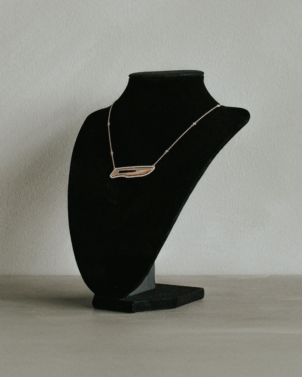 Scalpel Necklace on a black mannequin bust against a plain background