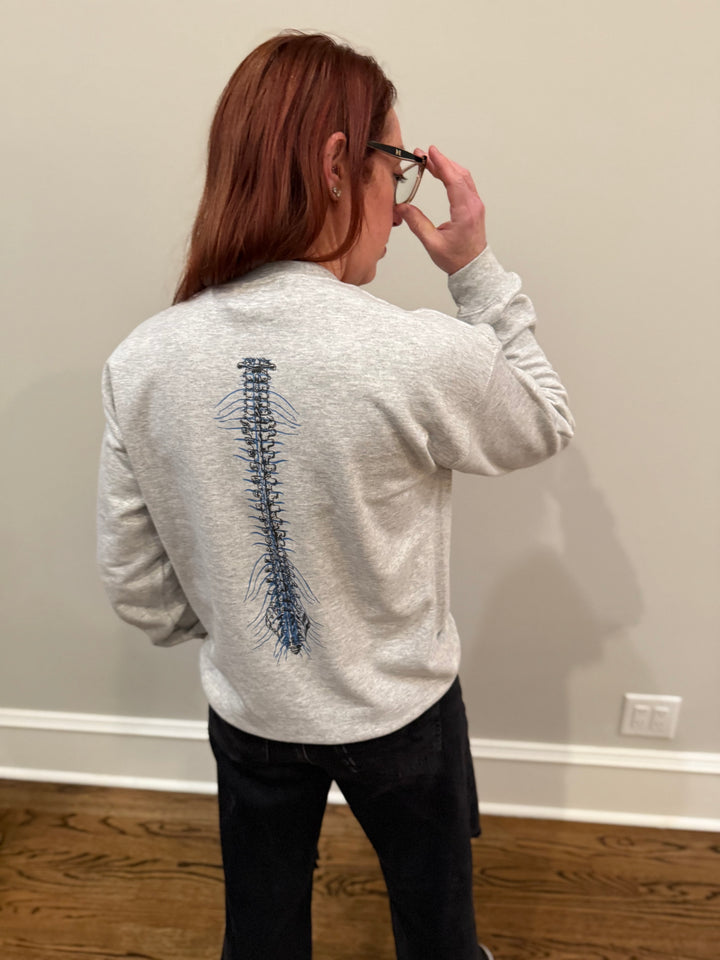 Ladyspinedoc wearing a gray spinal strenght sweatshirt with spine design on the back