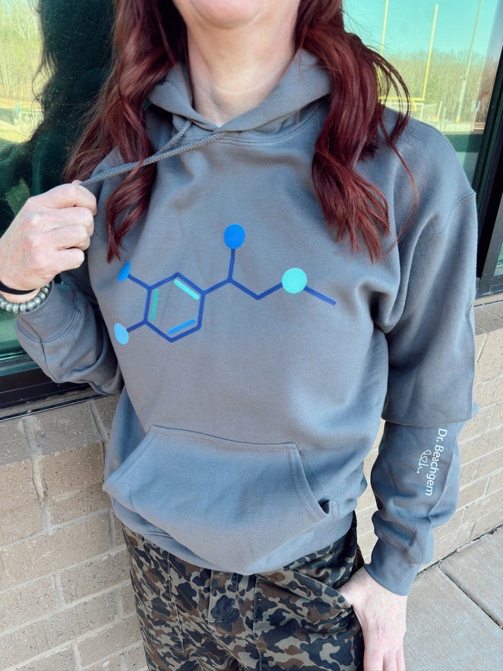 Ladyspinedoc wearing a gray hoodie with a multicolored blue and green epinephrine molecule design on the front 