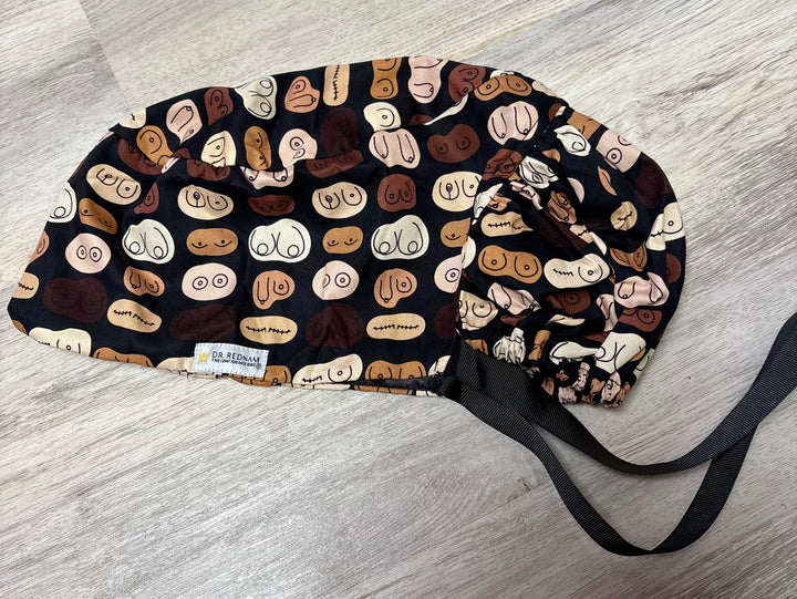 Scrub hat featuring a bold, anatomical breast print in diverse skin tones and shapes, designed by Dr. Rukmini Rednam (The Confidence Doc) in collaboration with Ladyspinedoc.