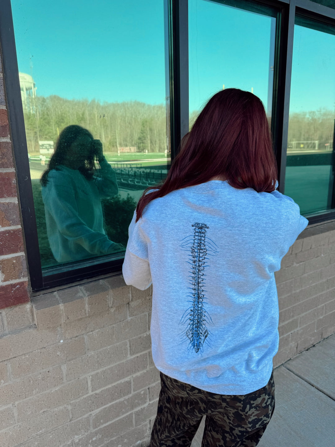 Ladyspinedoc showing back of gray Spinal Strength sweatshirt