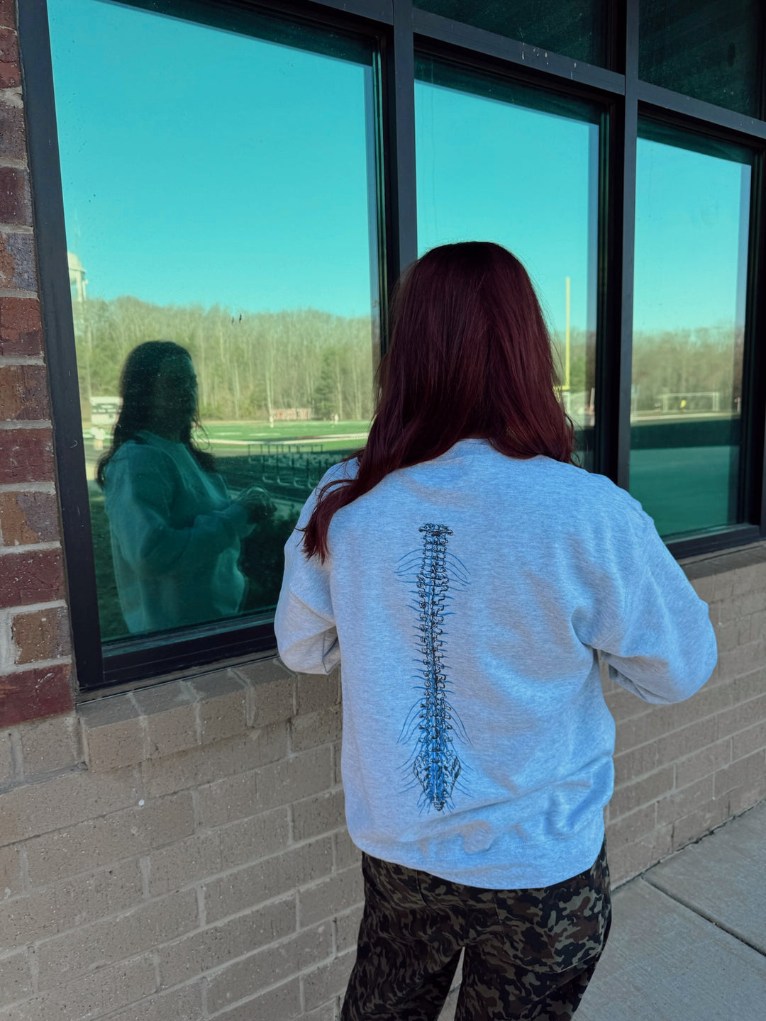 Ladyspinedoc showing back of gray Spinal Strength sweatshirt