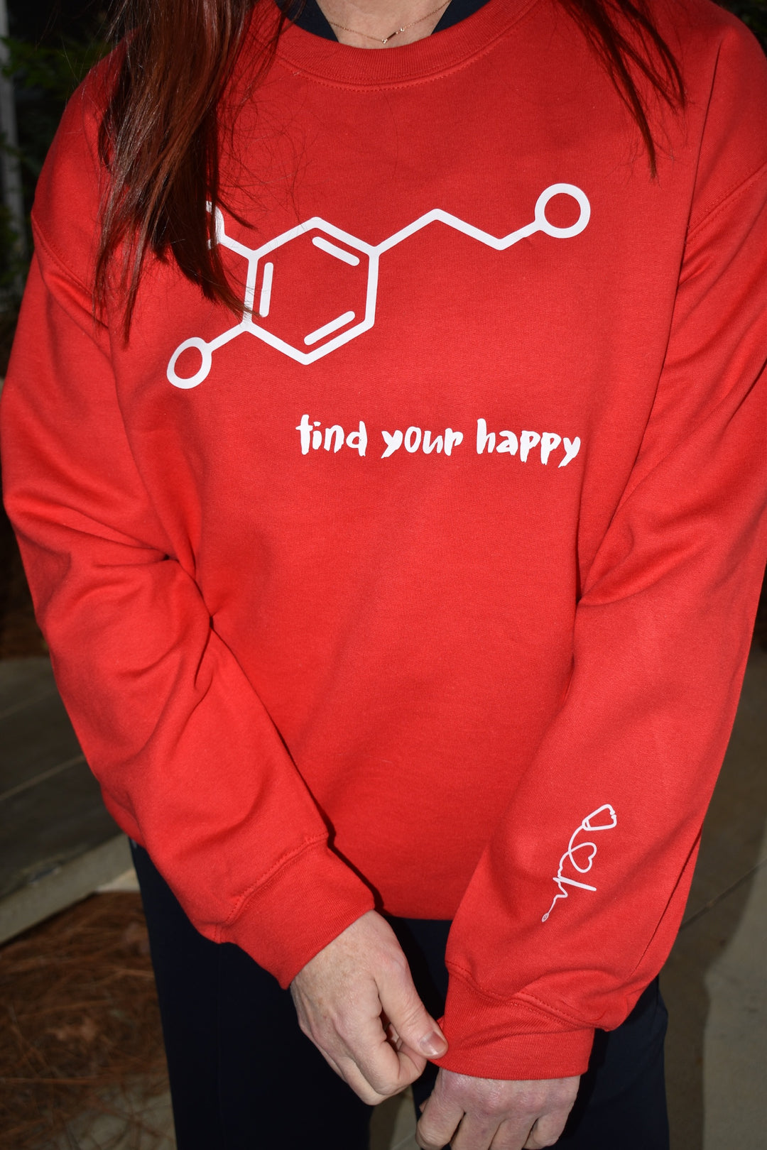 Dr. Betsy Grunch - Ladyspinedoc - wearing the red Dopamine Molecule Sweatshirt, and showing off the heart of medicine logo which symbolizes the heart of medicine printed on the inner left sleeve.
