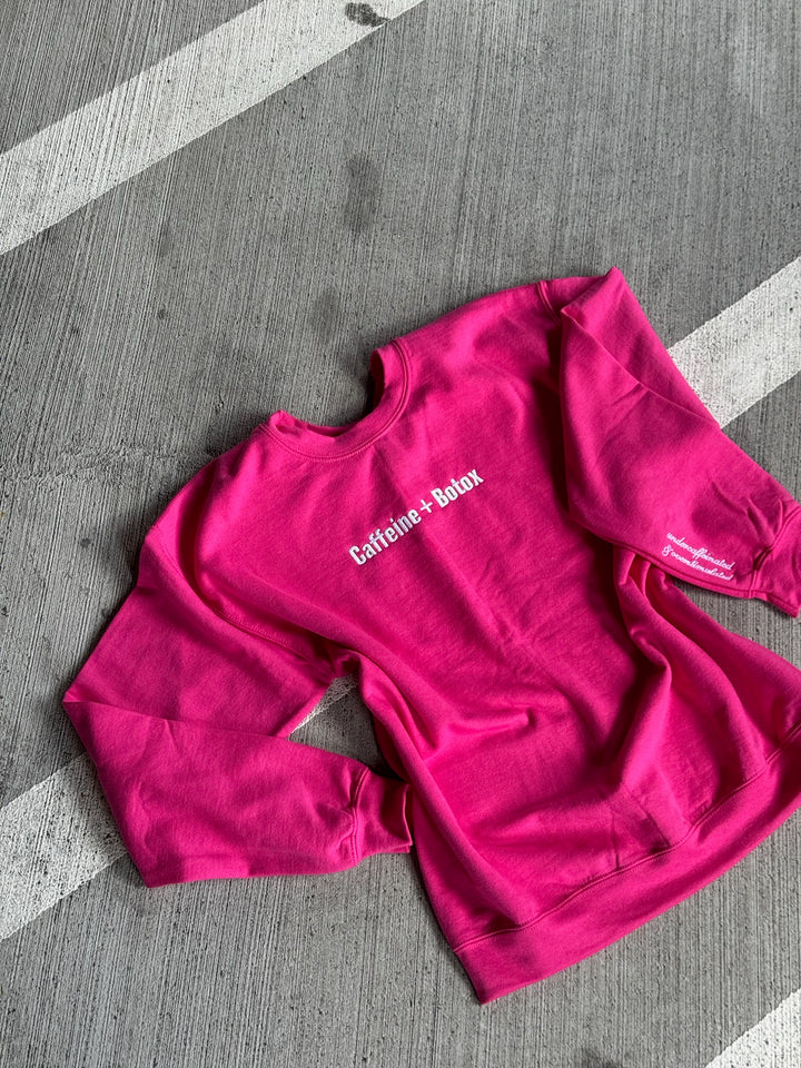Pink sweatshirt with Caffeine + Botox text on a gray surface