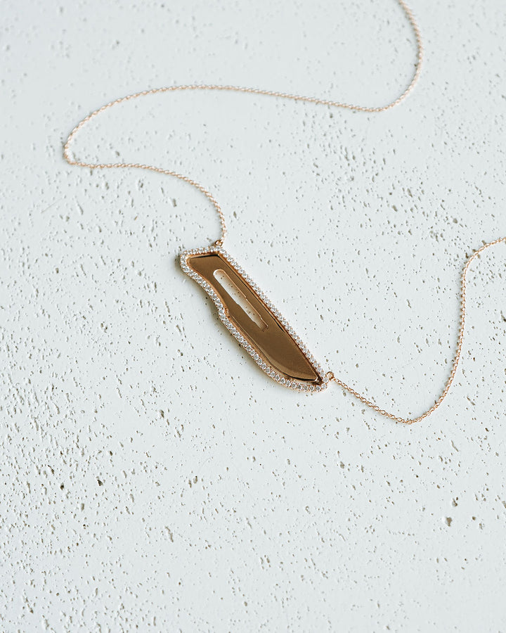 Necklace with a gold pendant on a light gray surface