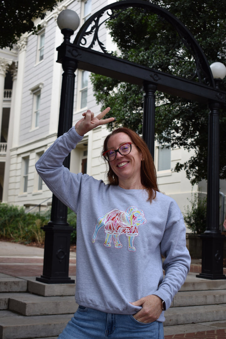 Person wearing a light gray sweatshirt with a colorful bulldog design, standing outdoors.