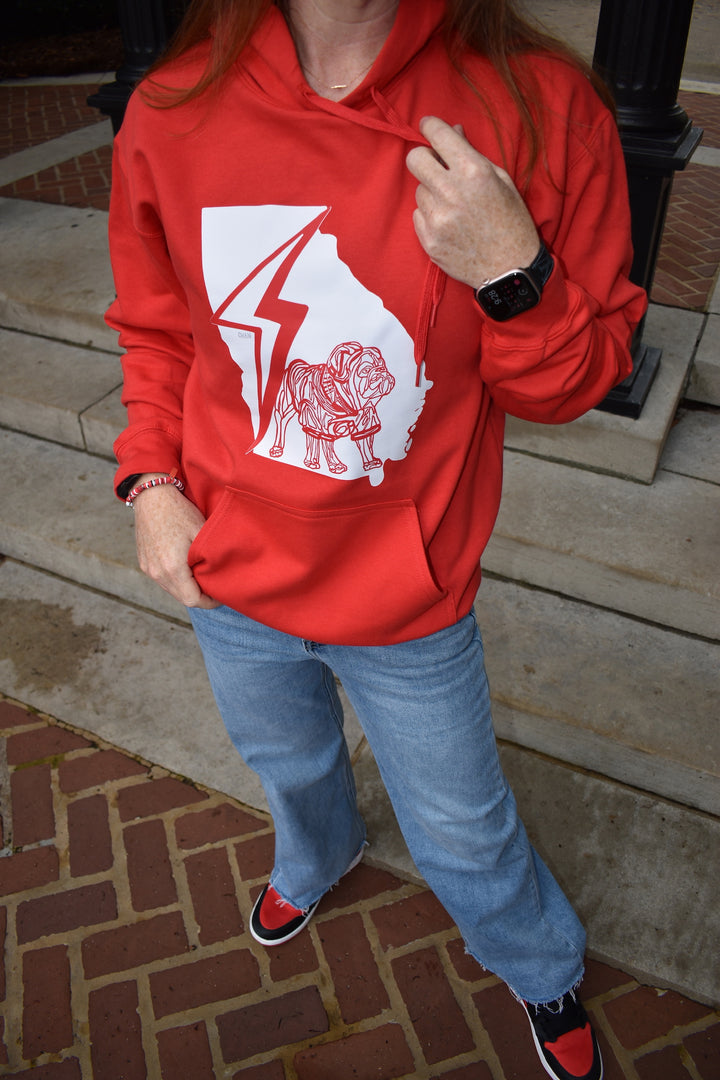 Person wearing a red hoodie with a graphic bulldog design on a brick pavement.