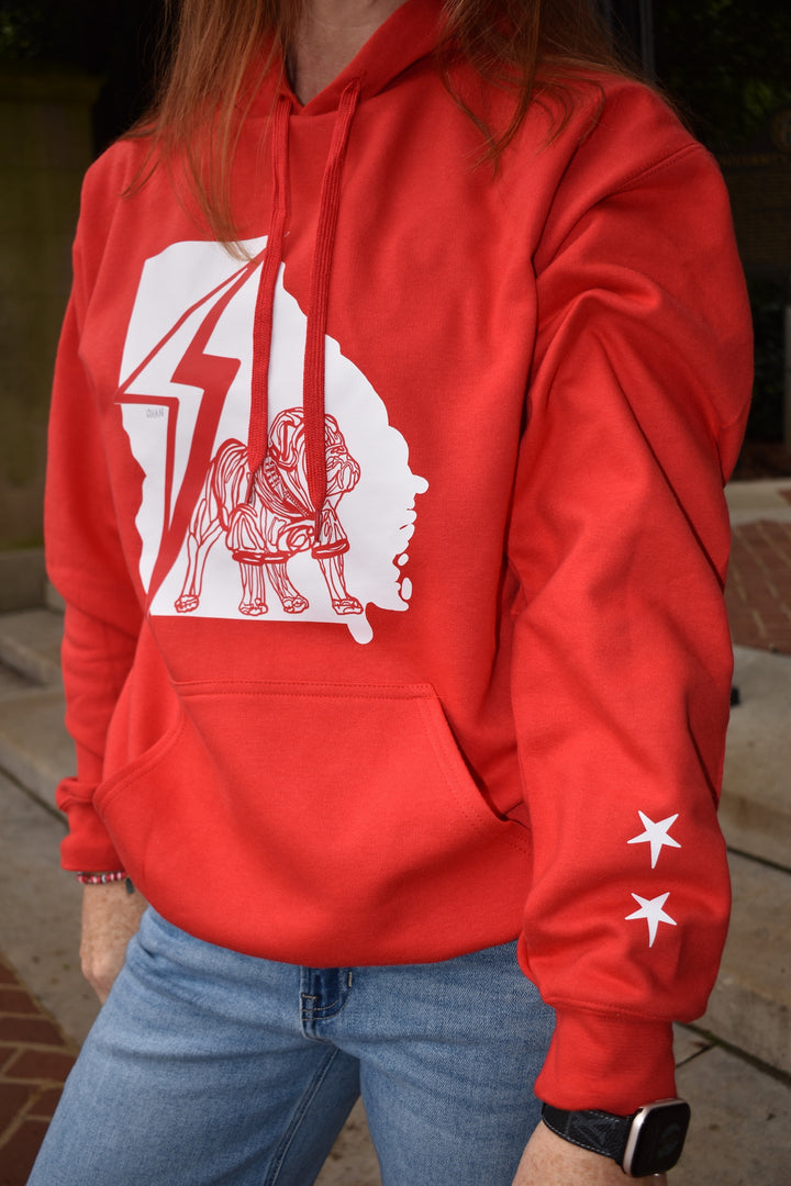 Person wearing a red hoodie with a white bulldog graphic design outdoors.