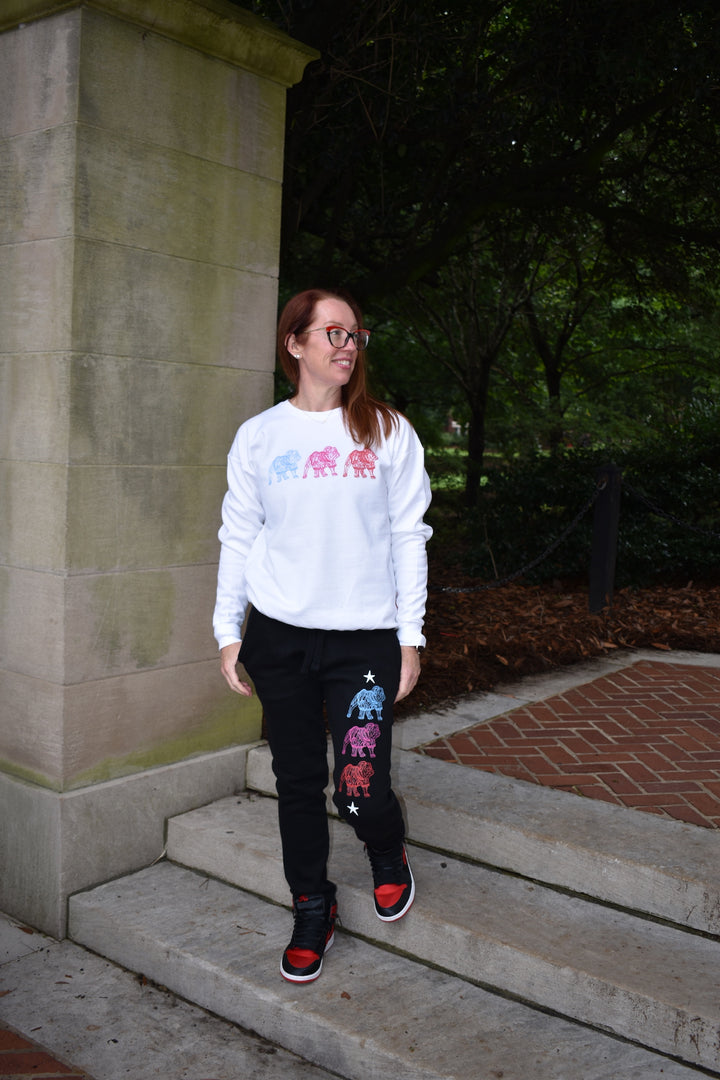 Person wearing a white sweatshirt with colorful designs on steps outdoors