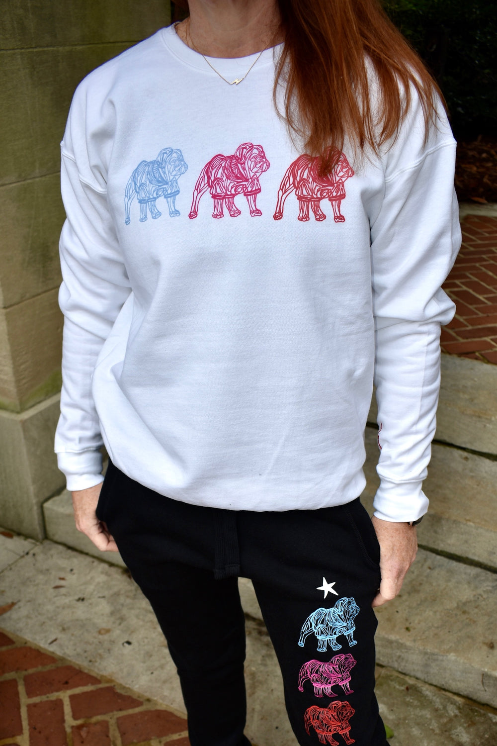 Person wearing a white sweatshirt with colorful bulldog designs and black pants with similar designs.