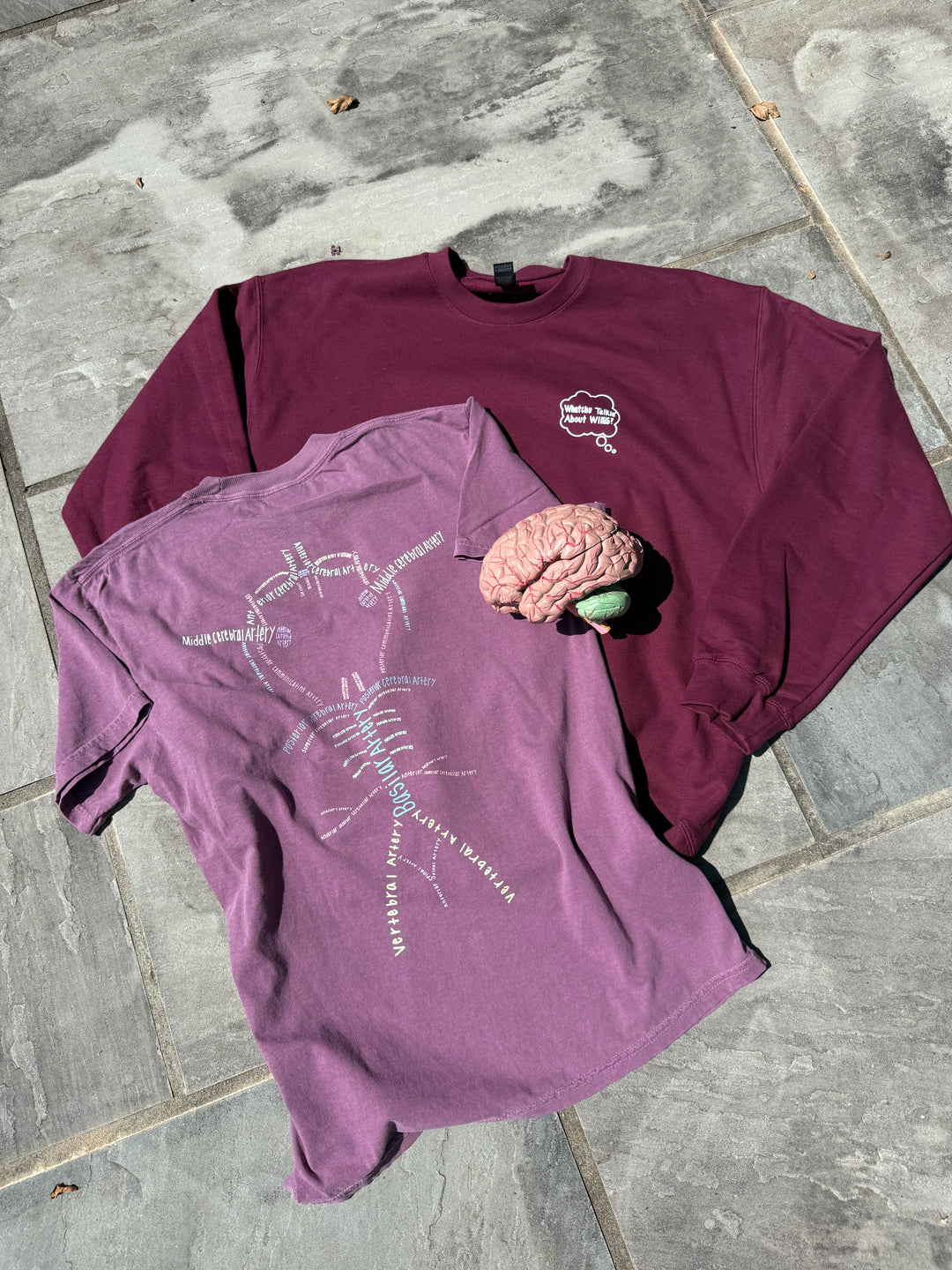 Two Whatchu Talkin’ About Willis shirts on a stone surface, along with an anatomical brain.