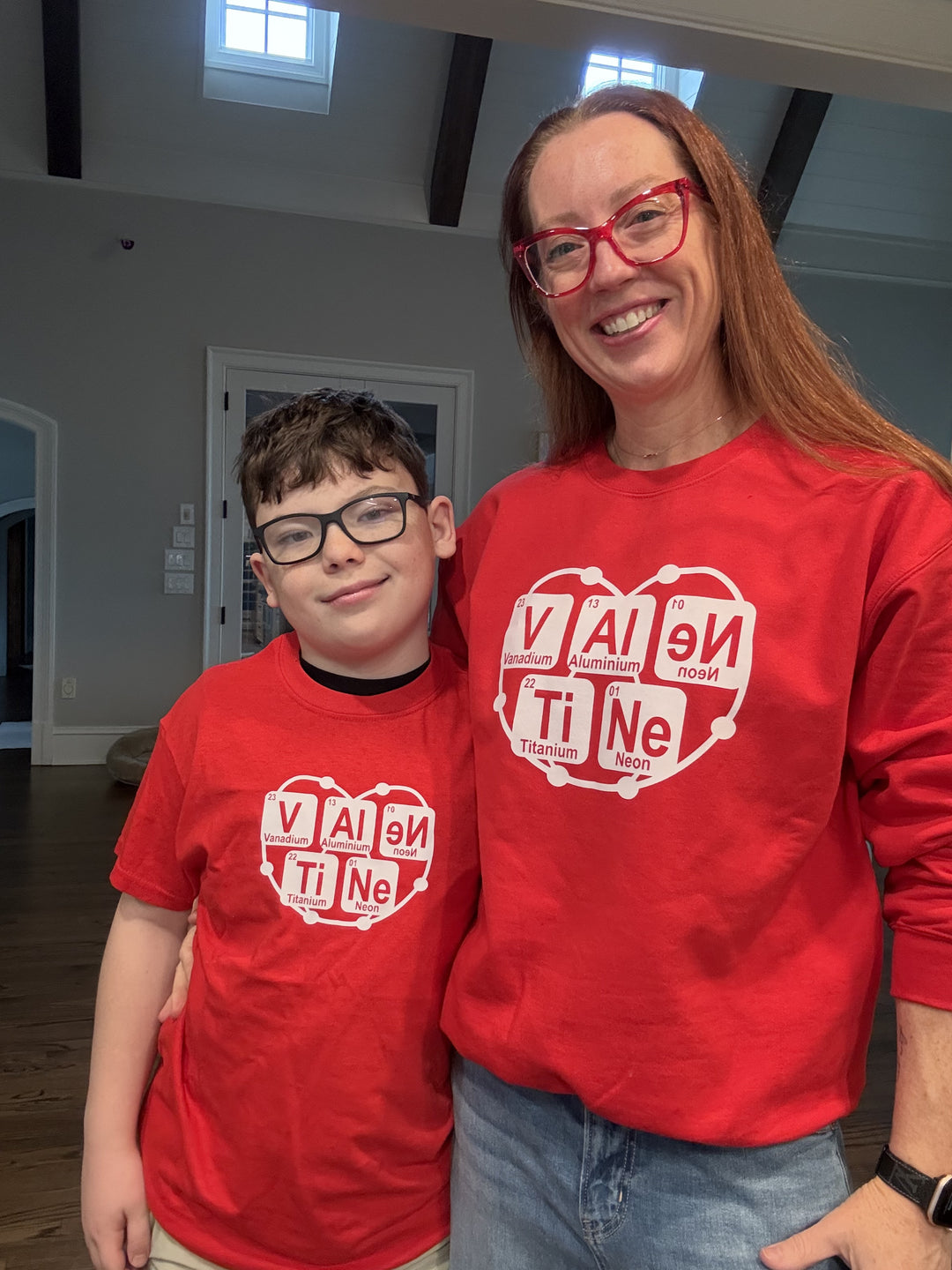 Dr. Betsy Grunch wearing the red Atomic Attraction crewneck sweatshirt with her son wearing the matching Atomic Attraction youth tee shirt.
