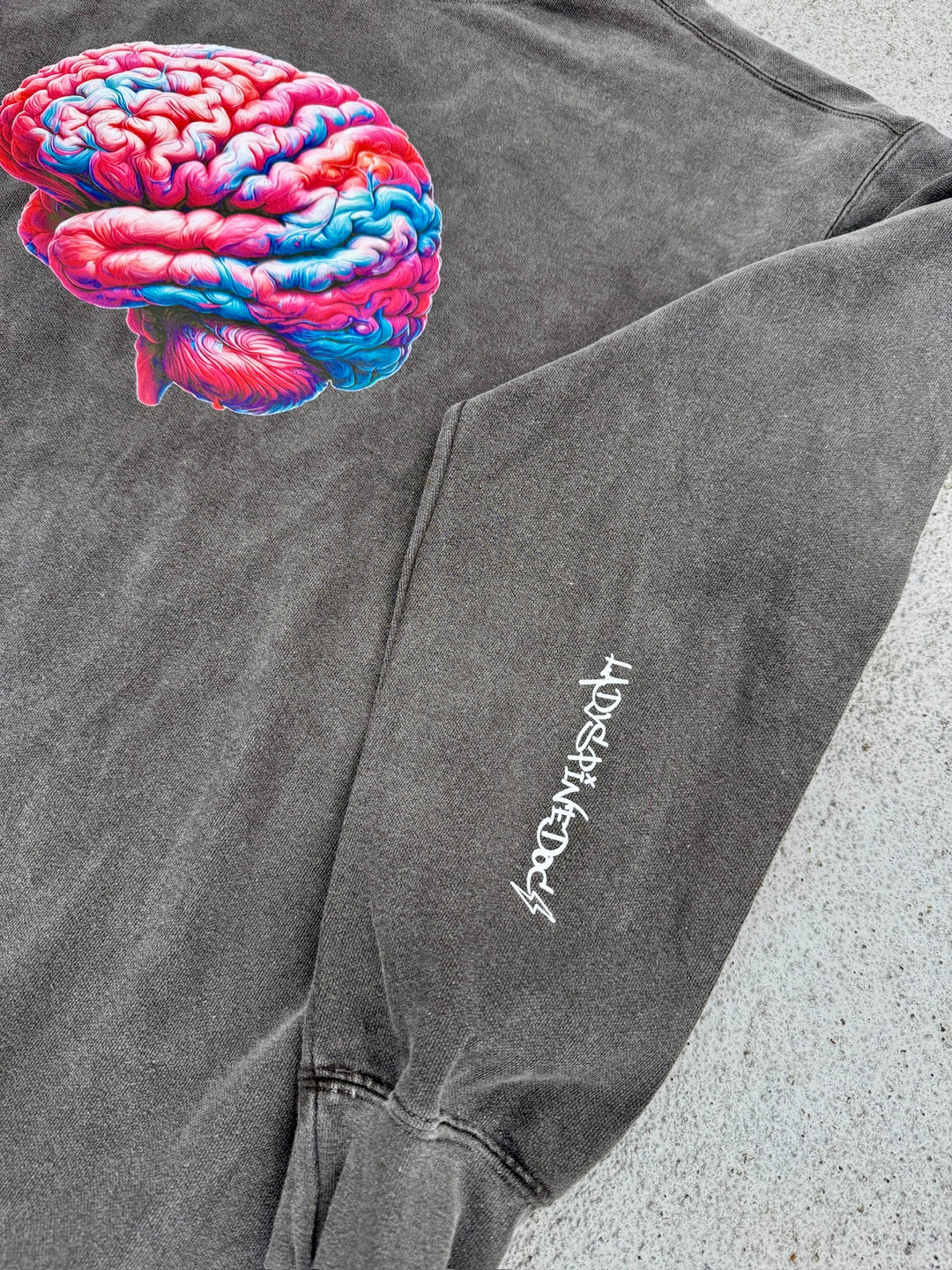 Gray sweatshirt with colorful brain on the front and white Ladyspinedoc logo on the left sleeve