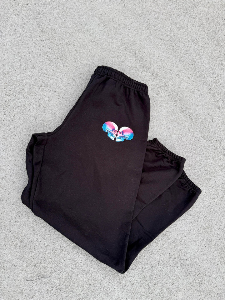 Super Skull Sweatpants - Folded Black Joggers with Skull Design laying on concrete