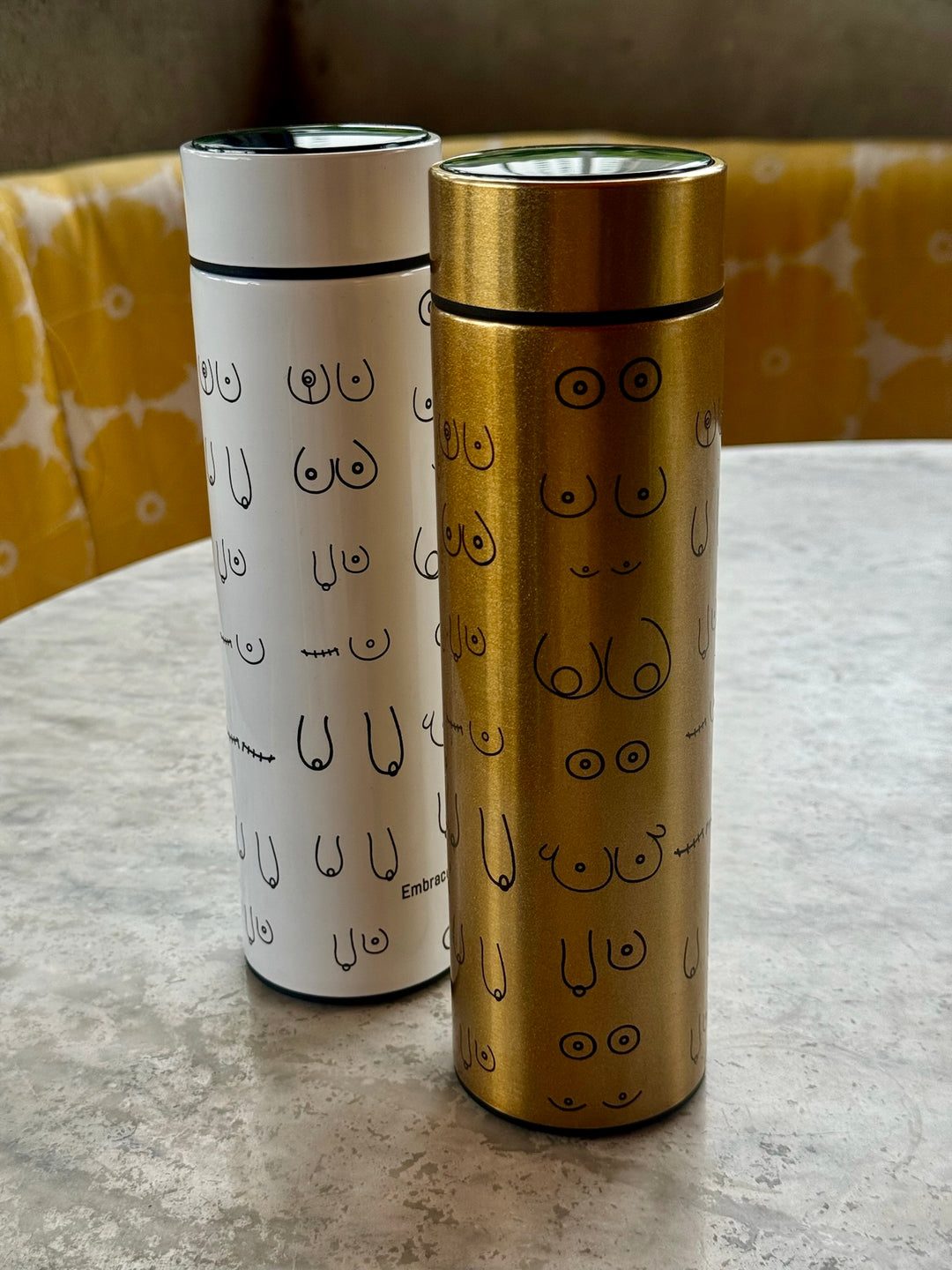 Smart water bottles in white and gold showing abstract line art of the female form representing breast reconstruction and recovery. Confidence Doc x Ladyspinedoc collaboration.