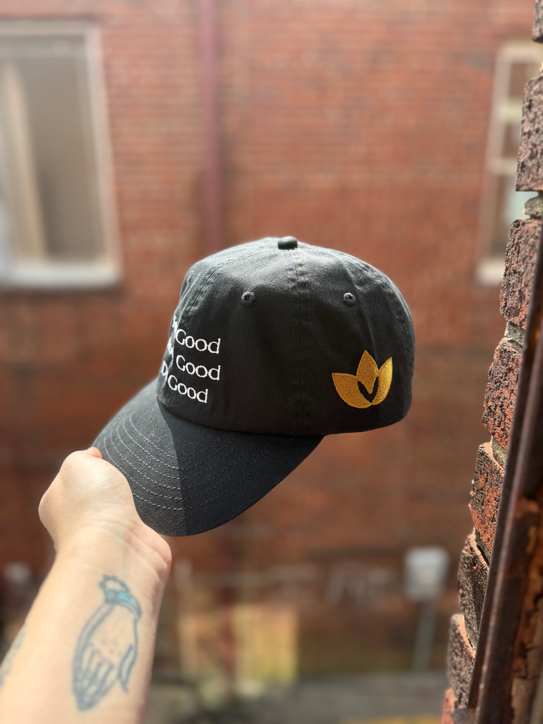 Black cotton ball cap showing embroidered motto on front and golden Confidence Doc logo on the side.