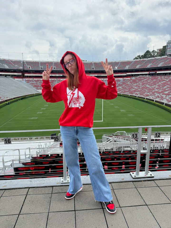 Person wearing a red hoodie with a white logo in a stadium setting