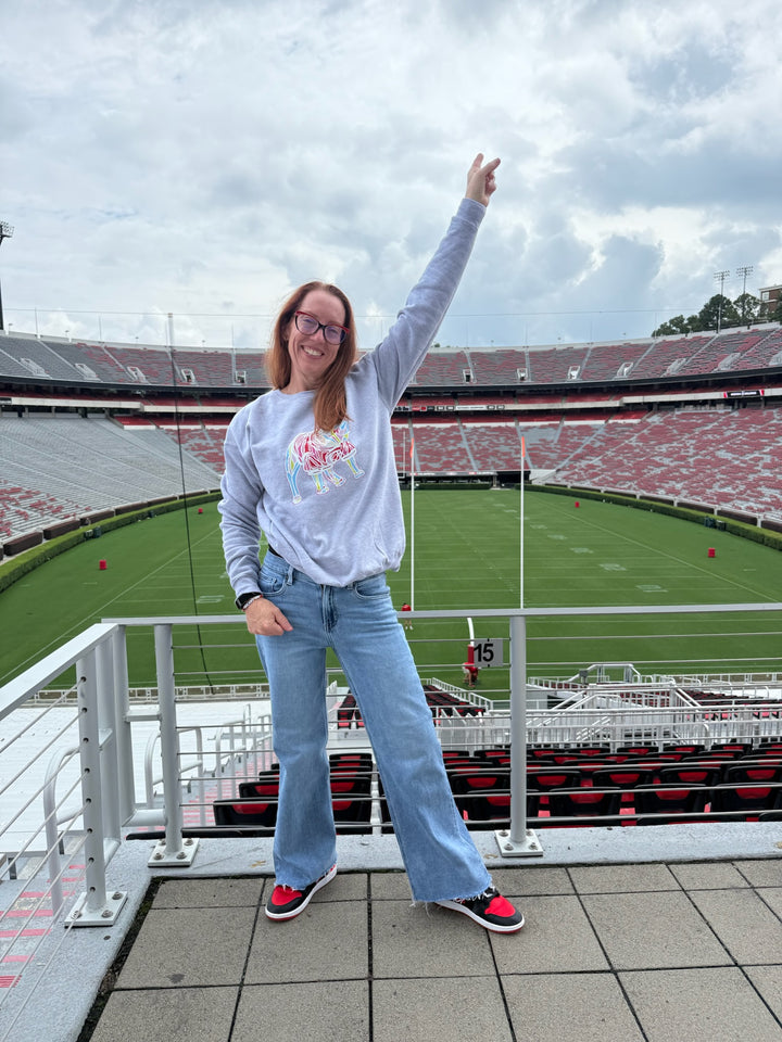 Person standing on a raised platform at a stadium, waving with one hand.