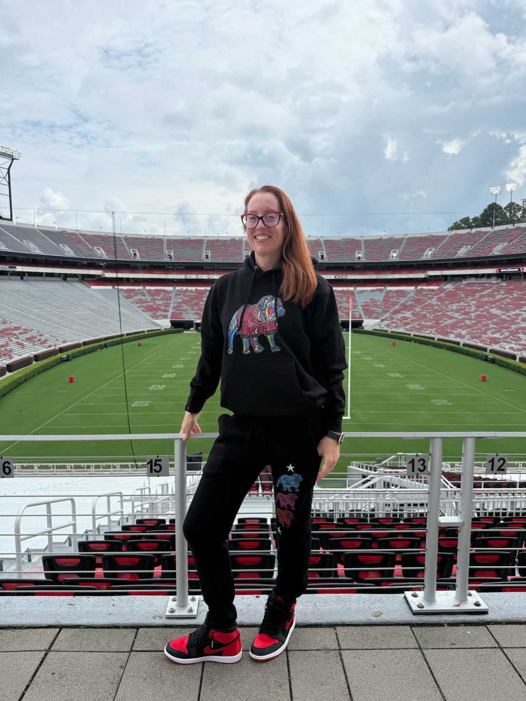 Ladyspinedoc wearing bulldog gear standing in front of a stadium with a cloudy sky