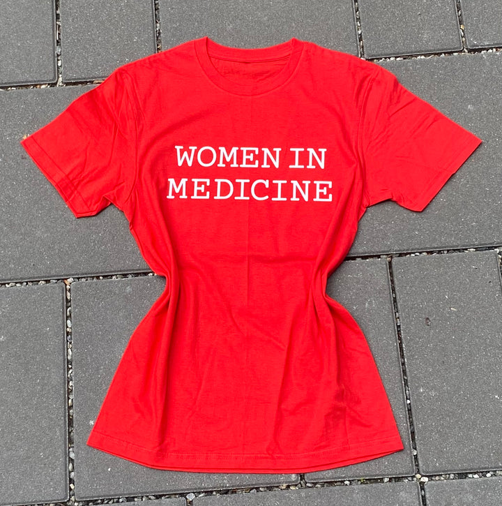 Red t-shirt with 'WOMEN IN MEDICINE' text on a gray tiled floor