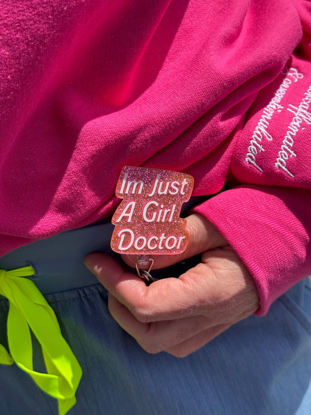 Person wearing a pink sweatshirt holding a keychain with 'I'm just a girl doctor' text.