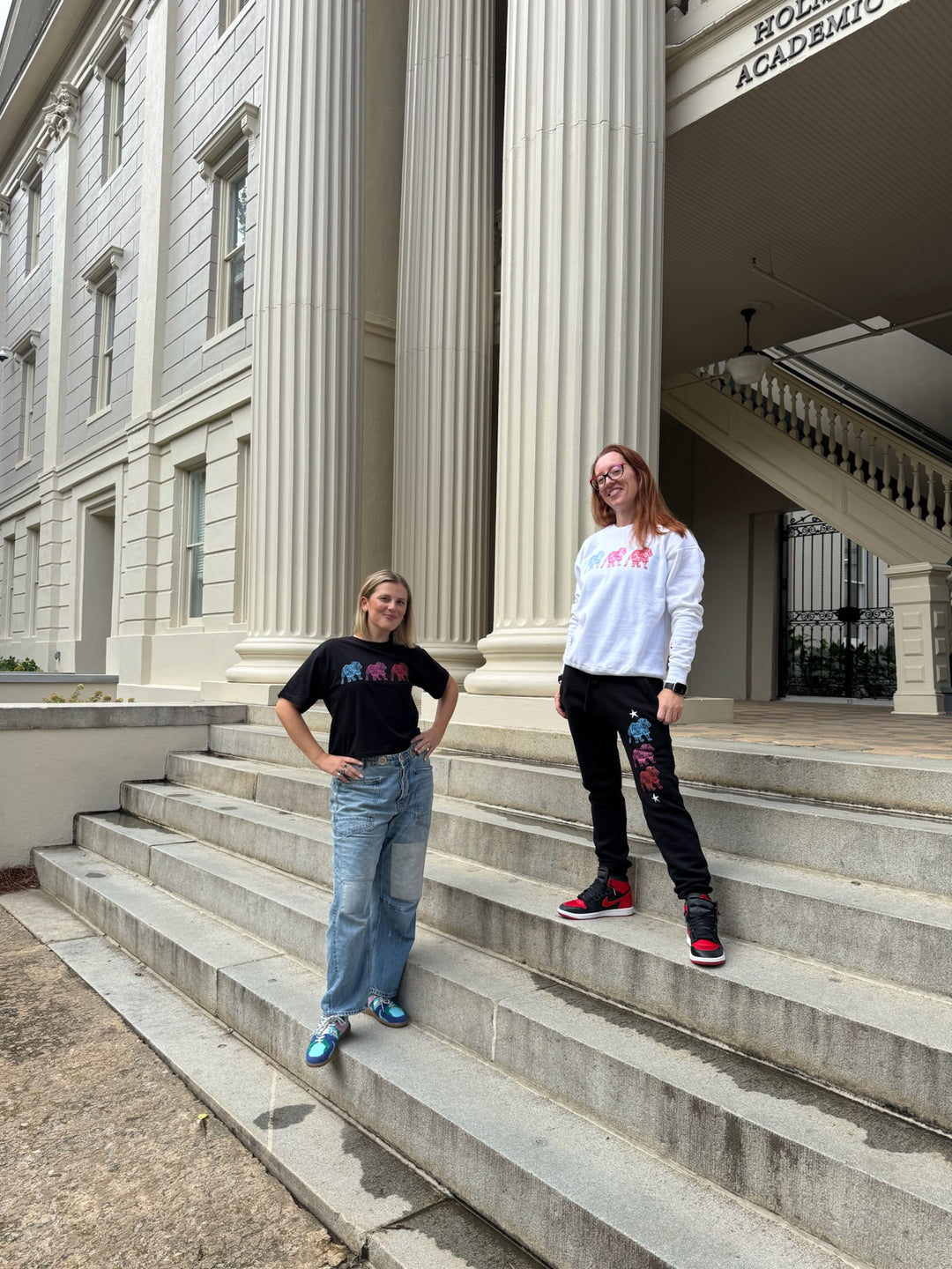 Two people standing on the steps of a classical building with columns.