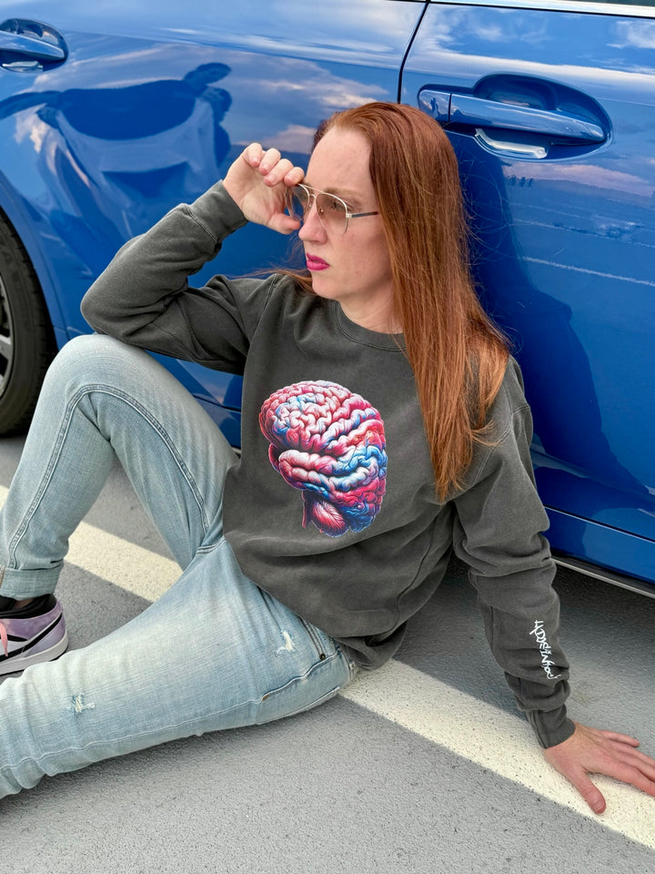 Dr. Grunch sitting on the ground wearing a dark gray crewneck sweatshirt with a colorful brain design on the front.