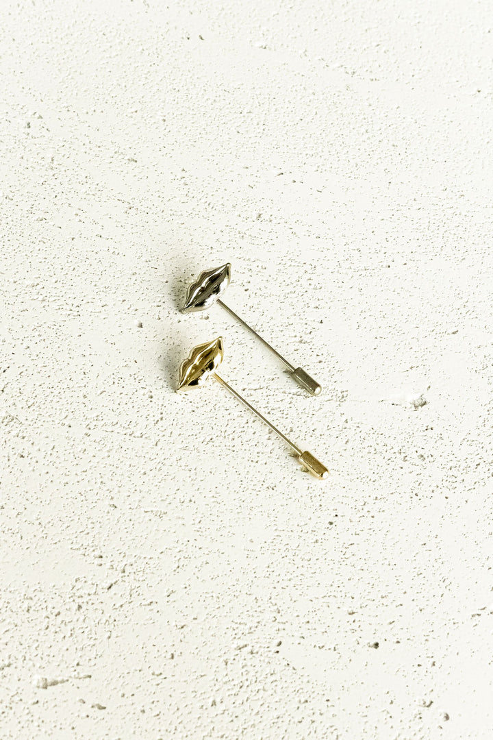 Two lips stick pins, one gold, the other silver