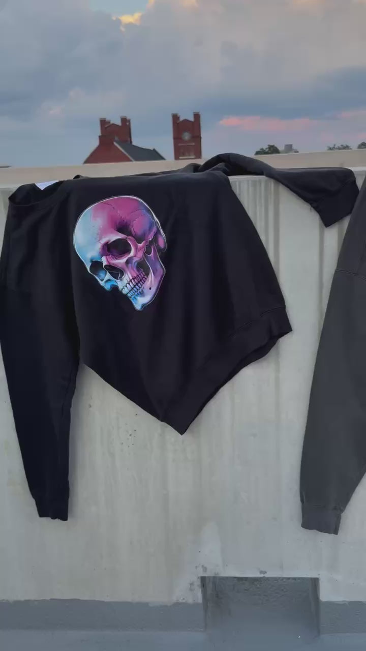 Video of Two black sweatshirts on a concrete wall, one with a colorful skull, the other with a colorful brain